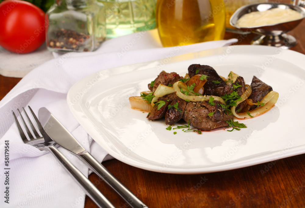 Fried chicken livers on plate on wooden table close-up