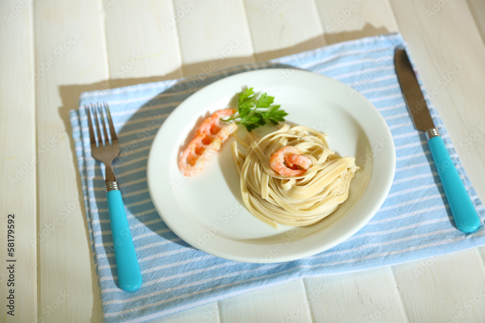 Pasta with shrimps on white plate, on wooden background