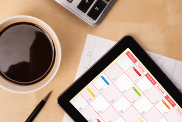 Wall Mural - tablet pc showing calendar on screen with a cup of coffee on a d