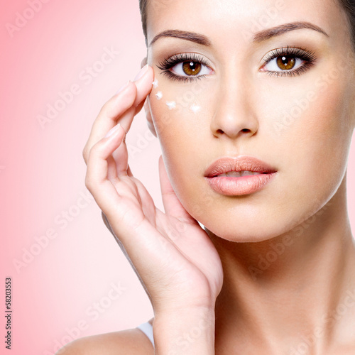 Fototapeta na wymiar woman with healthy face applying cosmetic cream under the eyes