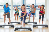 Instructor with fitness class performing step aerobics exercise