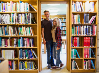 Poster - Young couple by bookshelves in the library