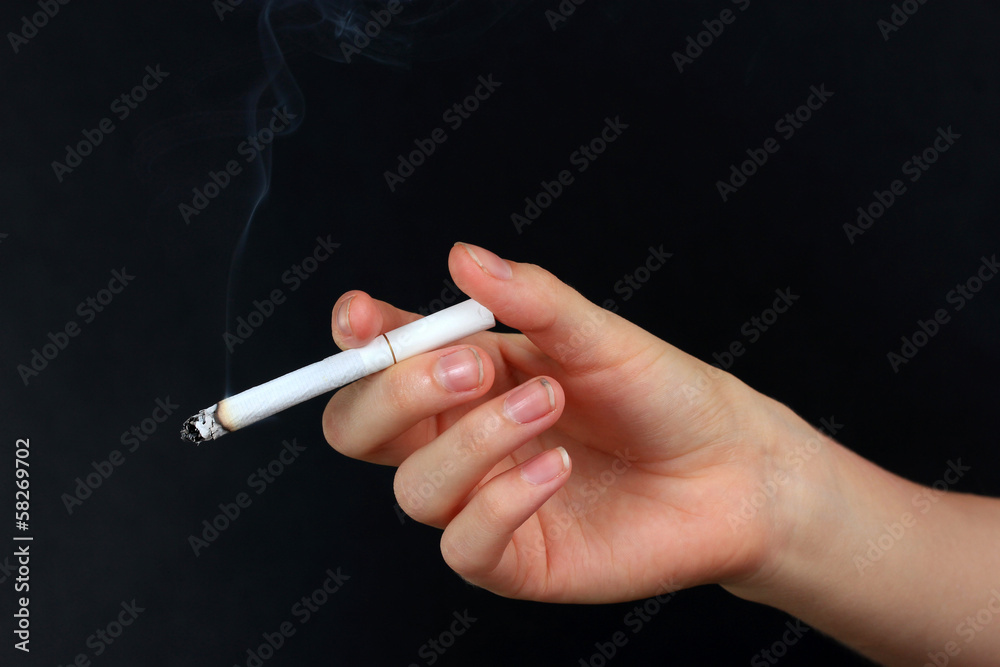 Woman hand holding cigarette with smoke, isolated on black Stock Photo