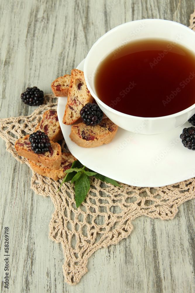 Cup of tea with cookies and blackberry on table close-up