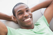 © lightwavemedia - Close up of smiling relaxed Afro man lying on sofa