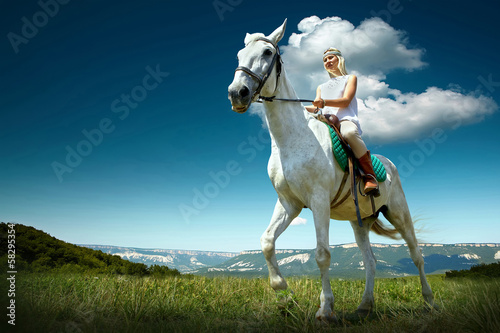Foto-Stoff bedruckt - Young horsewoman riding on white horse, outdoors view (von Andrii IURLOV)