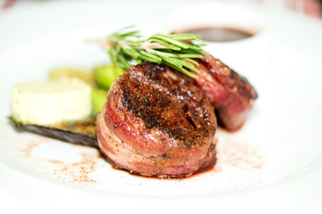 grilled steak wrapped in bacon with grilled vegetables close up