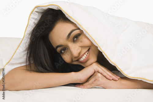 Photo Portrait of a woman looking through a quilt