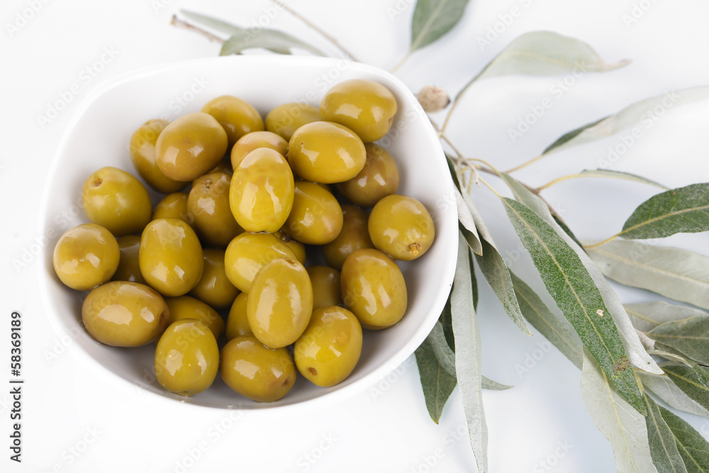 Olives in bowl with branch isolated on white