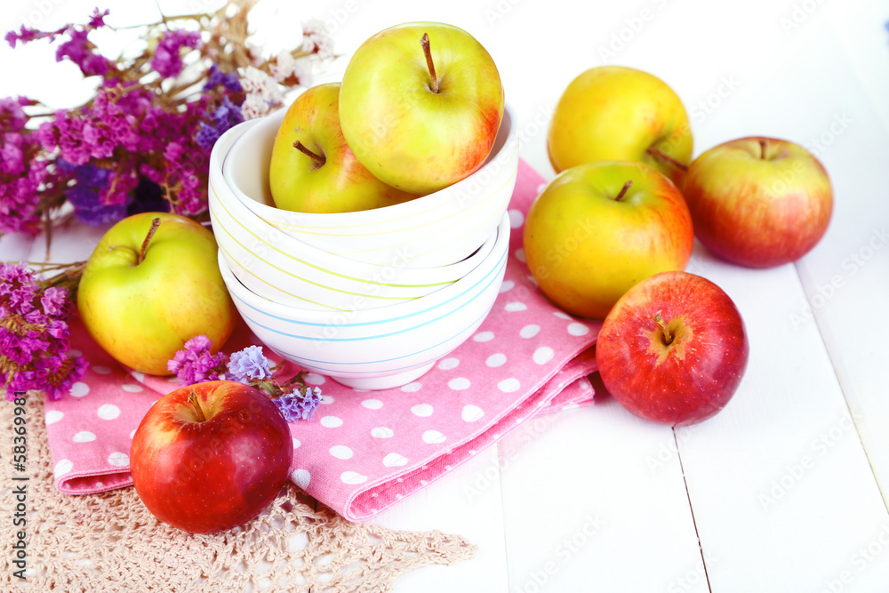 Juicy apples on plate on white wooden table