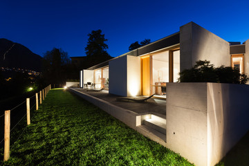 Modern house in cement, view from the garden, night scene