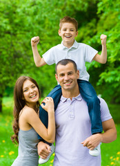 Fototapete - Happy family of three. Dad keeps son on shoulders