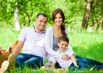 Fototapete - Happy family of three has picnic in green park
