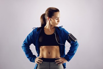 Wall Mural - Female athlete listening music with cell phone