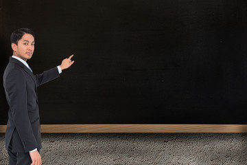 Poster - Composite image of serious asian businessman pointing