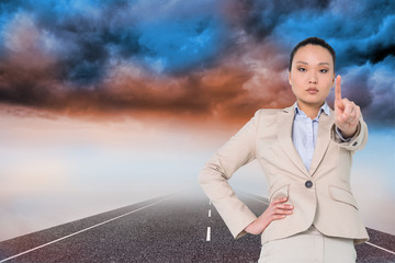 Poster - Composite image of unsmiling asian businesswoman pointing