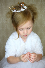 Wall Mural - A little girl in crown looks at the rhinestones