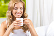 © vgstudio - Young woman drinking coffee or tea, at home