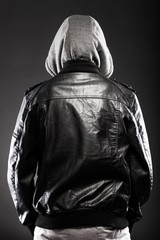 Young man in leather jacket and hood rear view