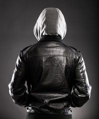 Young man in leather jacket and hood rear view