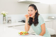 © lightwavemedia - Young woman eating salad in the kitchen