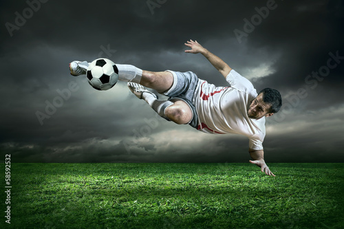 Foto-Stoff bedruckt - Football player with ball in action under rain outdoors (von Andrii IURLOV)