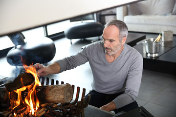 Mature man in modern house preparing fire