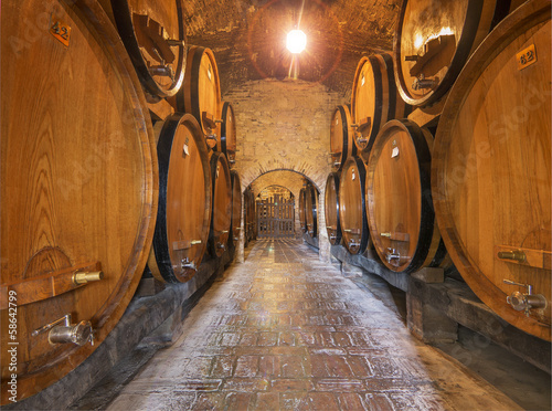 Fotomural Wine barrels stacked in the old cellar of an Italian winery.