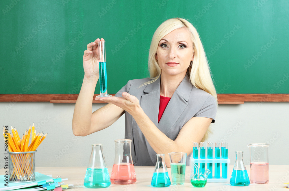 Chemistry teacher with tubes sitting at table