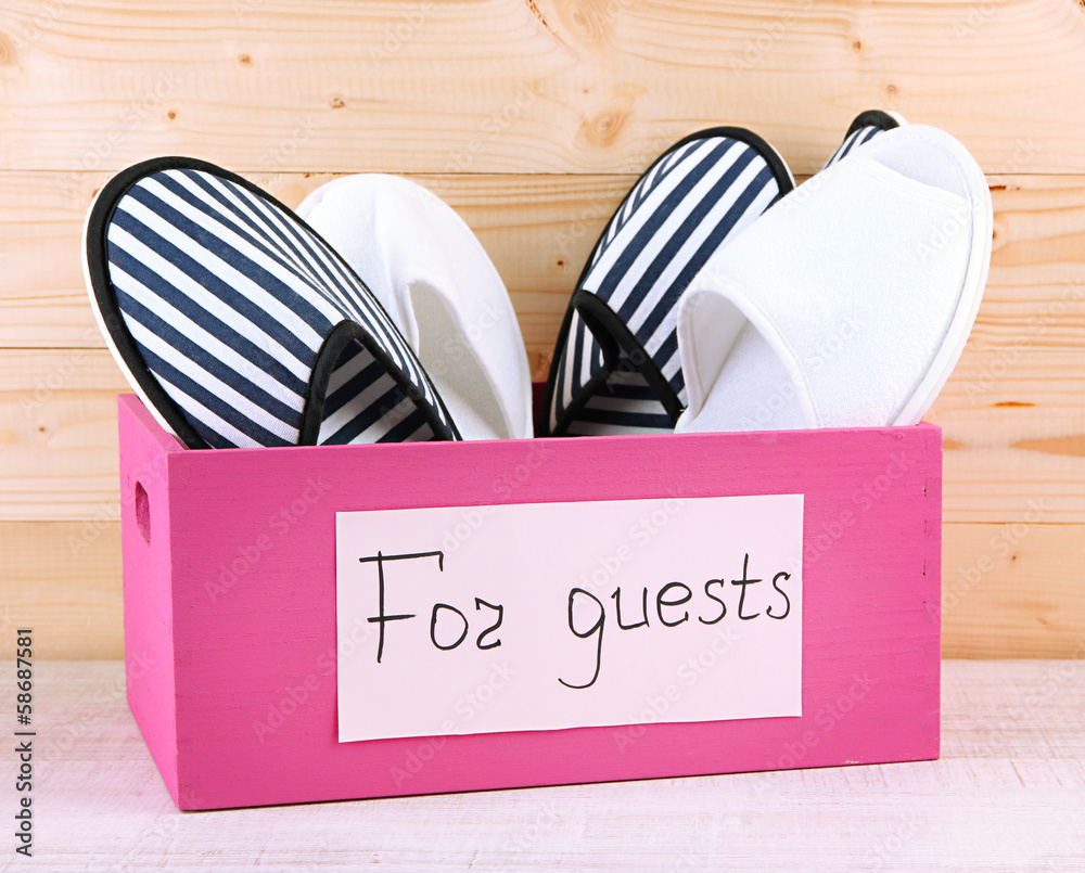 Slippers in wooden box on table on wooden background