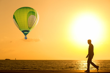 Wall Mural - Silhouette Man walking on the beach at sunset