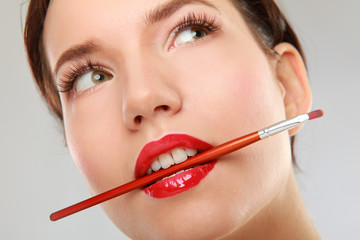 Woman's lips holding make up brush.