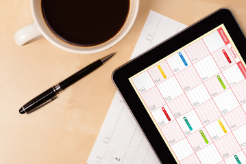 Wall Mural - tablet pc showing calendar on screen with a cup of coffee on a d
