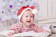 © golovianko - Happy baby boy in Santa`s hat under the Christmas tree