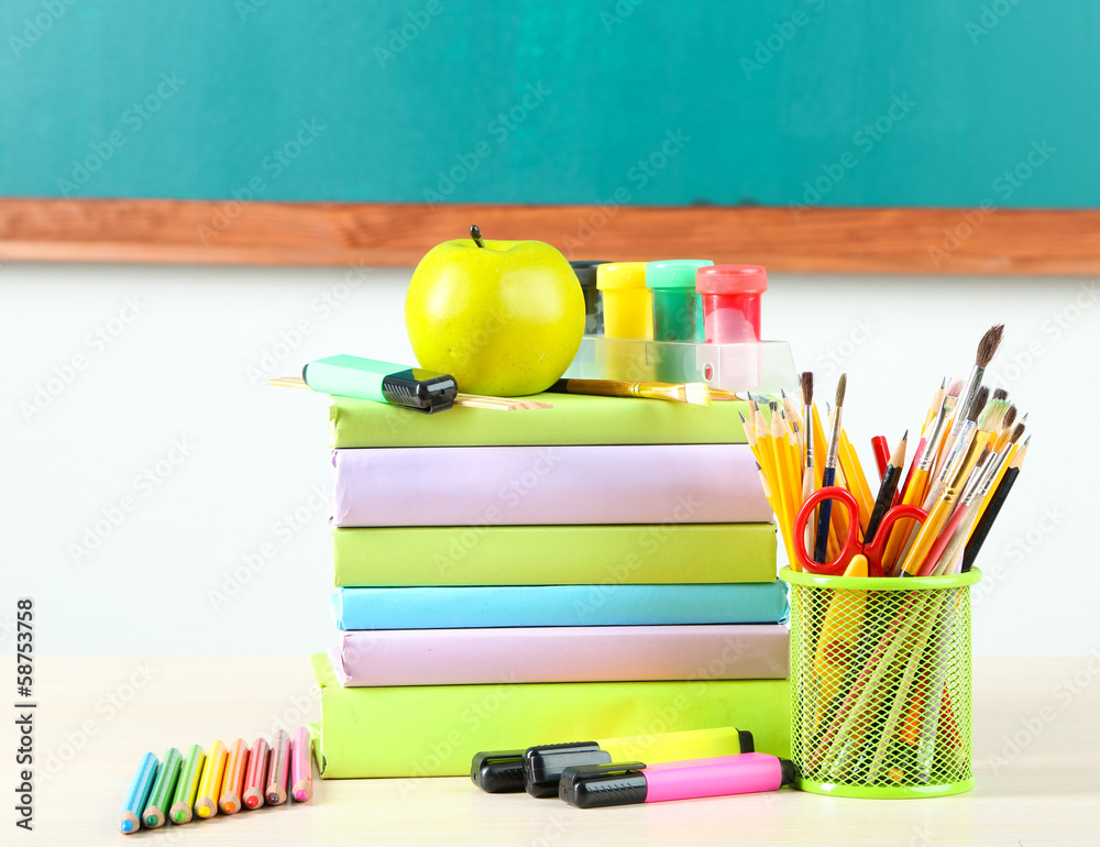 School supplies on table on blackboard background