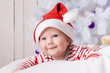 © golovianko - Smiling baby boy in Santa`s hat under the Christmas tree
