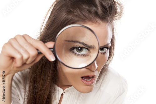 Fotografía shocked young woman looking through a magnifying glass