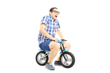 Wall Mural - Excited young male riding a small bicycle