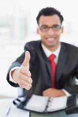 Wall Mural - Blurred businessman offering a handshake at desk