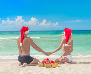 Wall Mural - Lovers couple in santa hats and many golden packed presents on s