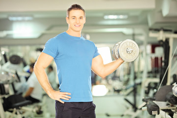 Canvas Print - Smiling muscular man lifting weight in fitness club