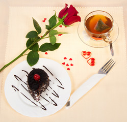 Romantic table setting with cup of tea, cake and roses