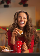 Wall Mural - Happy young woman enjoying christmas snacks in kitchen