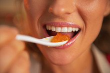Closeup On Happy Young Woman Eating Orange Jam