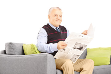 Wall Mural - Senior gentleman on a modern sofa with newspaper looking at came