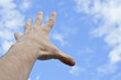 hand stretched to the blue cloudy sky