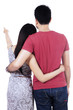 © Creativa Images - Young couple pointing at copy space