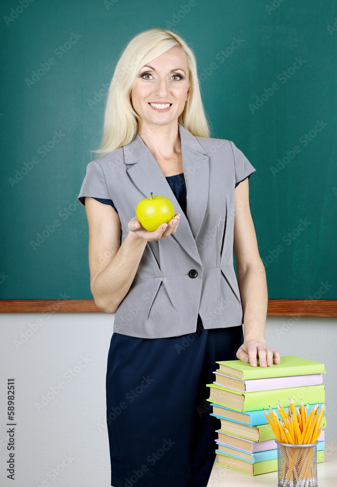 School teacher with apple on blackboard background