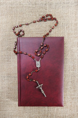 Wall Mural - Holy Bible and rosary on jute background. Copy space