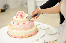 Bride And Groom Cutting Elegant Cake With Roses